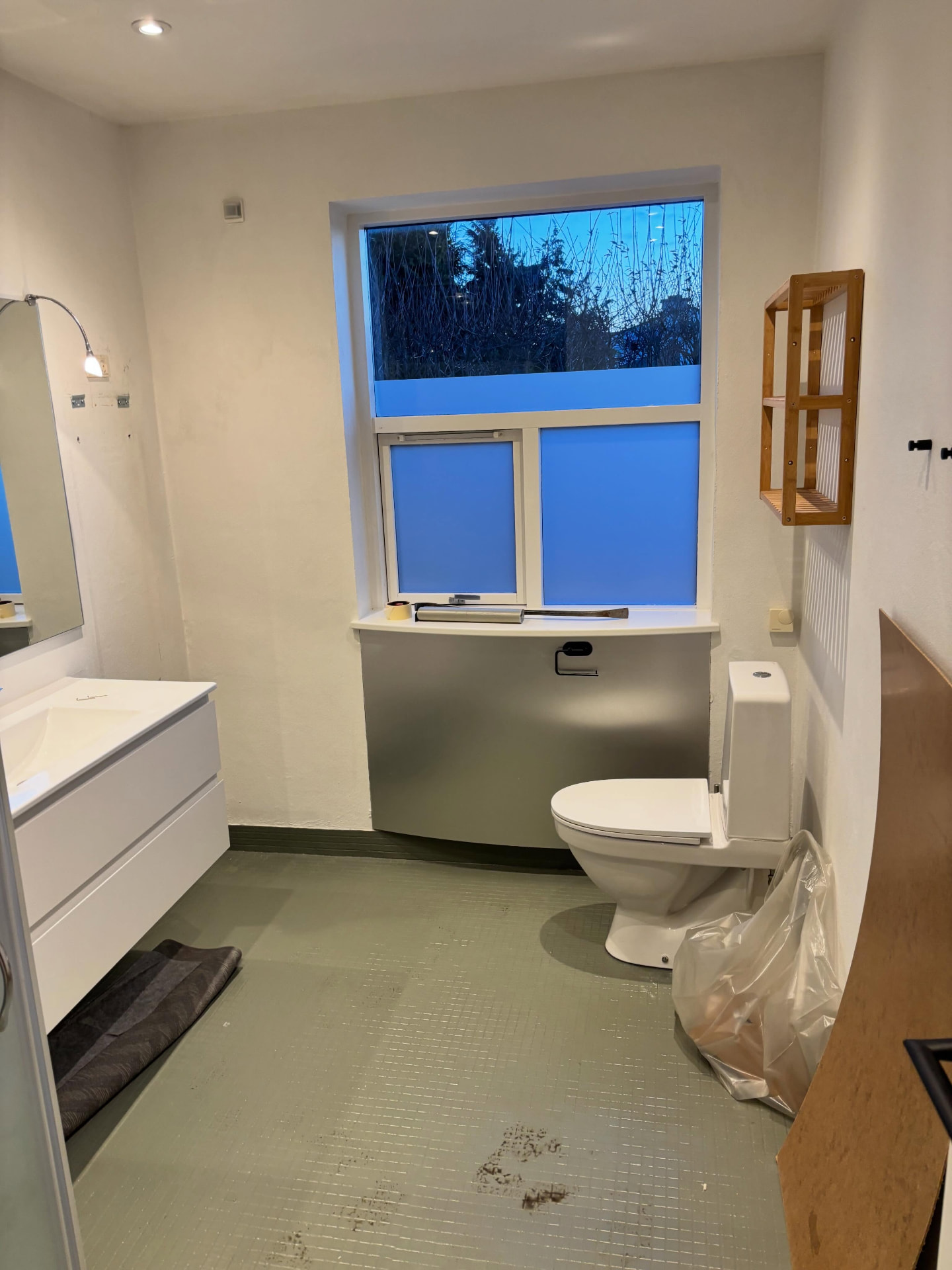 Det gamle badeværelse med grønne mosaikfliser, gulvstående toilet og forvæg