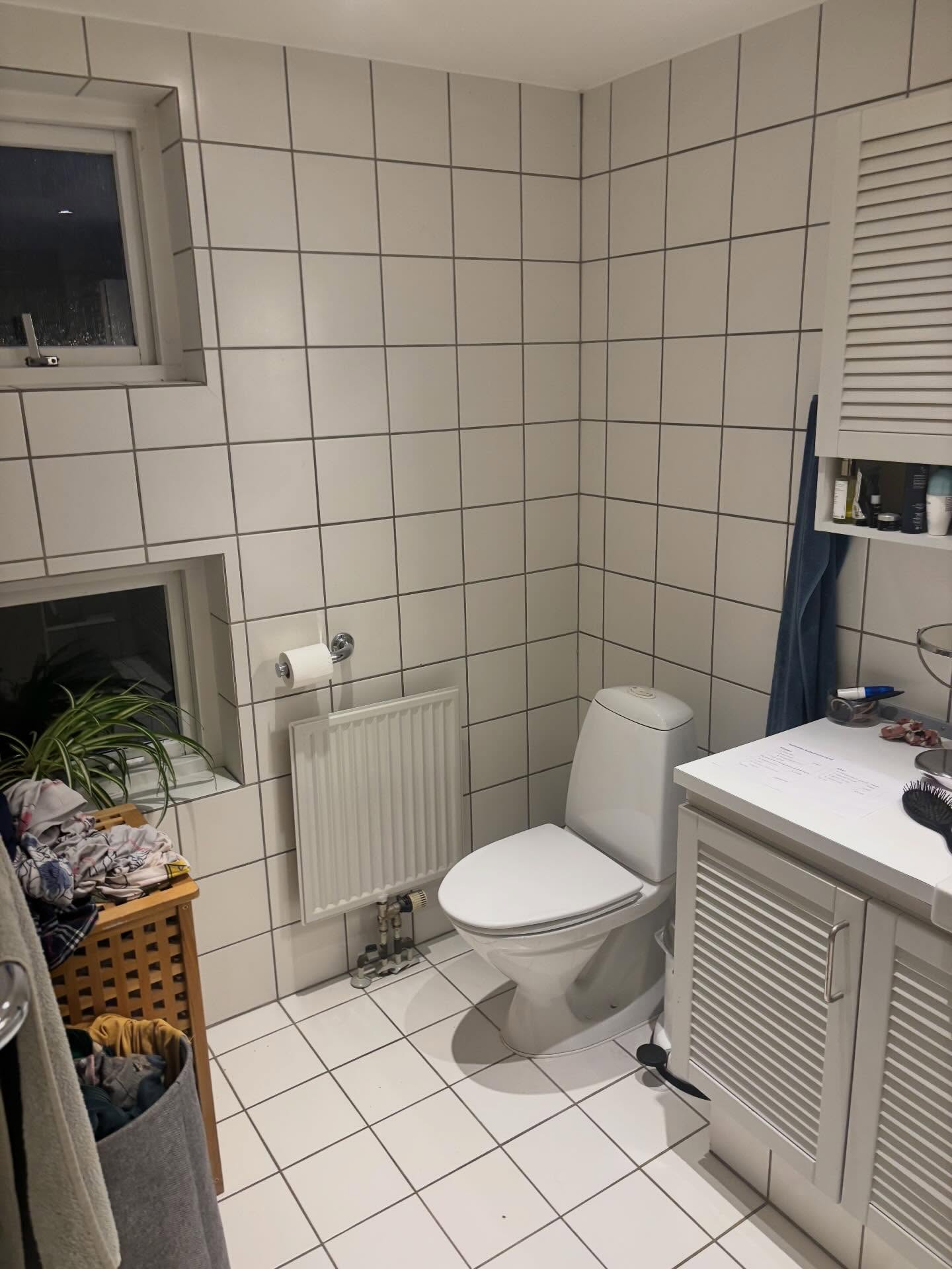 Gammelt gulvstående toilet med radiator og hvide fliser