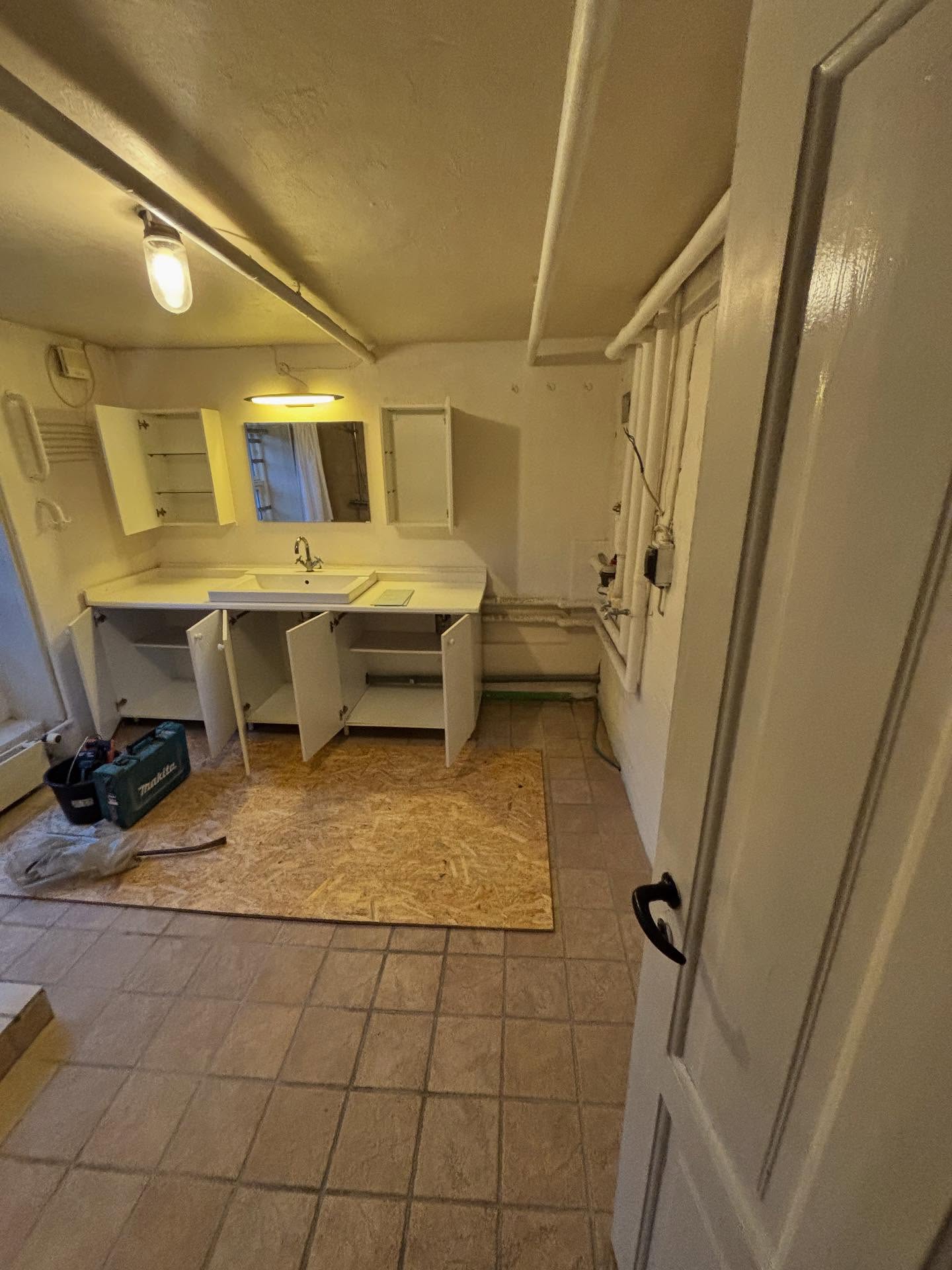 Kælderbadeværelset før renovering med gamle klinker og hvidt vaskemøbel